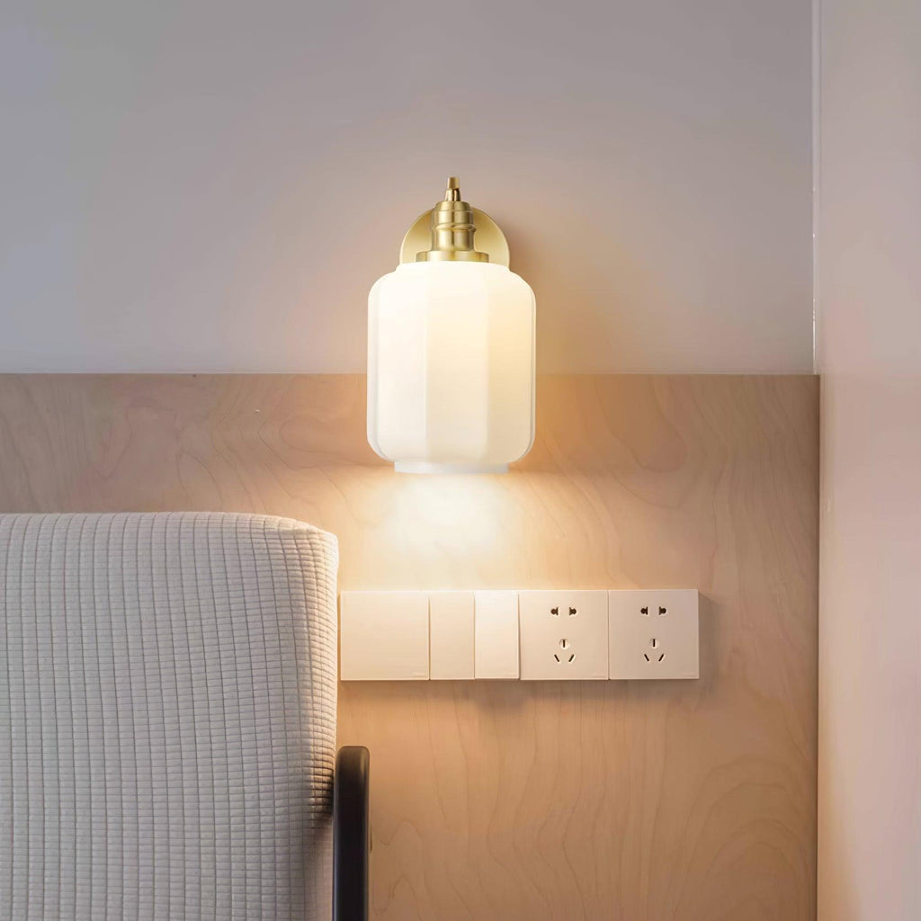Clérachic Fluted White Glass Wall Sconce lit above a bed on birch panelling, a warm reading glow beside the wall switches.