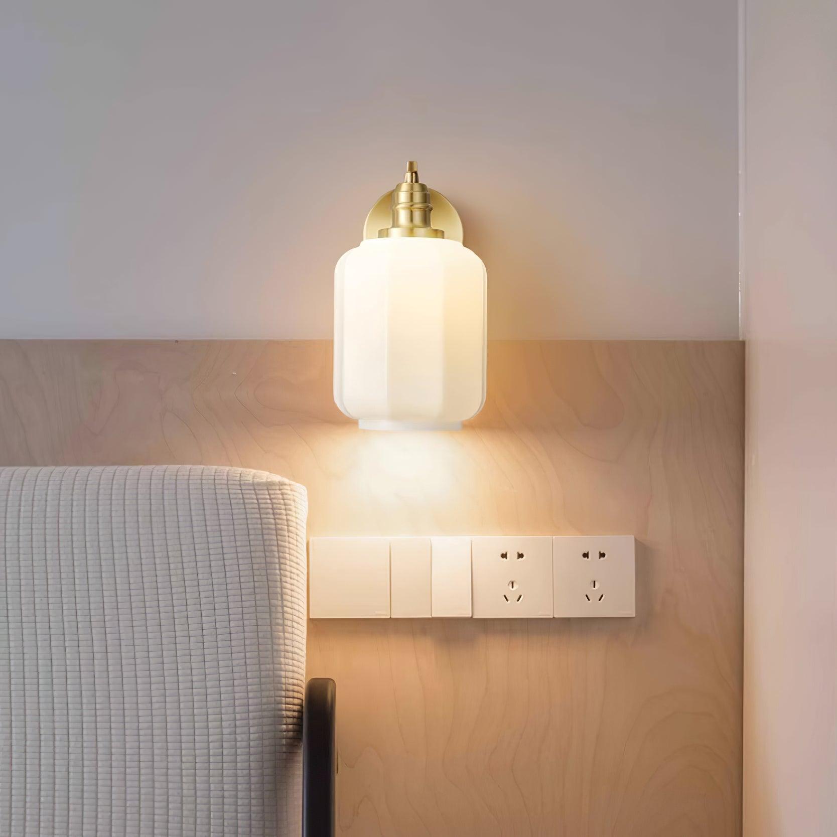 Clérachic Fluted White Glass Wall Sconce lit above a bed on birch panelling, a warm reading glow beside the wall switches.