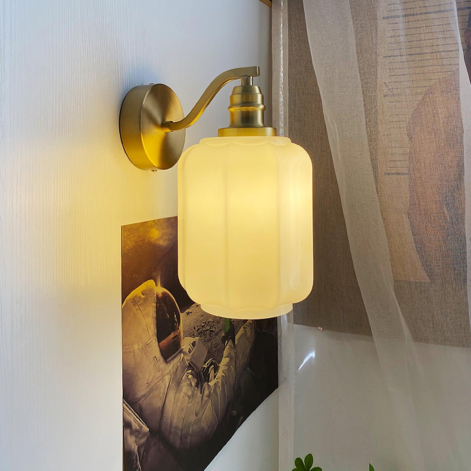 Side view of the lit Clérachic Fluted White Glass Wall Sconce, the shade creamy where the bulb sits behind eight shallow flutes.