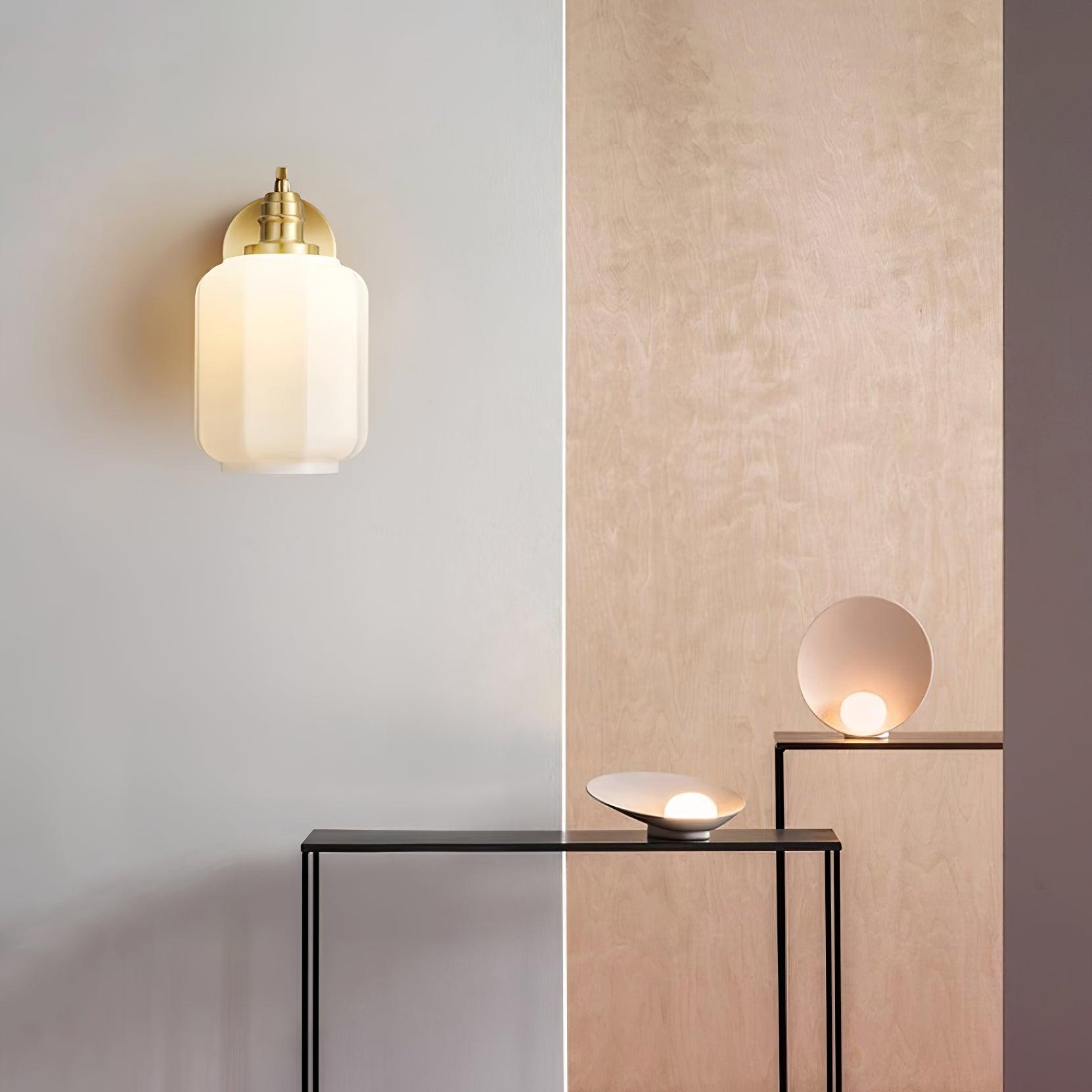 Clérachic Fluted White Glass Wall Sconce lit on a pale wall beside birch panelling and two console tables with small lamps.