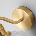 Close detail of the round brushed brass backplate on the Clérachic Fluted White Glass Wall Sconce and the arm joining it.