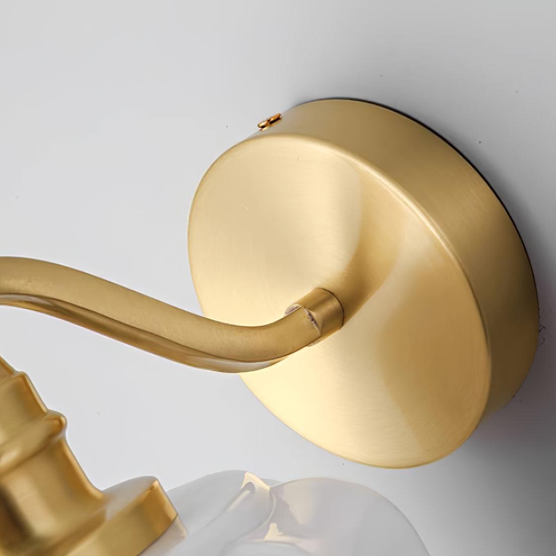 Close detail of the round brushed brass backplate on the Clérachic Fluted White Glass Wall Sconce and the arm joining it.
