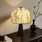 Clérachic black table lamp with a bamboo-print shade lit in a corner, with a dark vase and a leafy branch on a console.