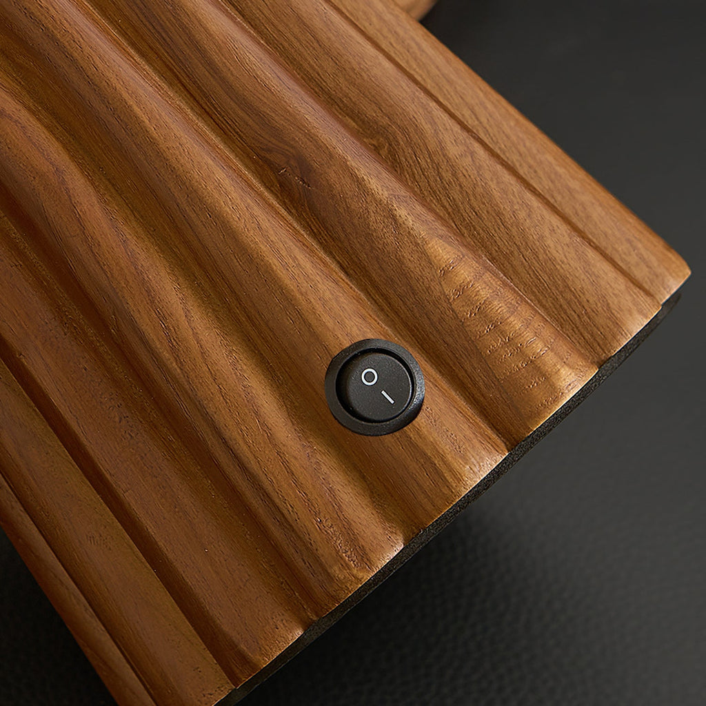 Close view of the fluted walnut-colour wood and the small round on-off switch on the base of this Clérachic table lamp.