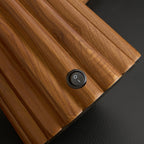 Close view of the fluted walnut-colour wood and the small round on-off switch on the base of this Clérachic table lamp.