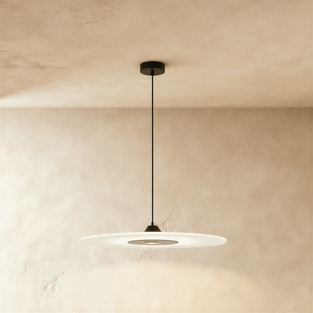 Clérachic large frosted disc pendant with black fittings, glowing softly beneath a limewash plaster ceiling and wall.