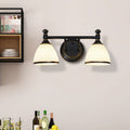 The two-light Clérachic frosted bell vanity light glows above a home bar of bottles and glassware, beside a shelf of dishes.