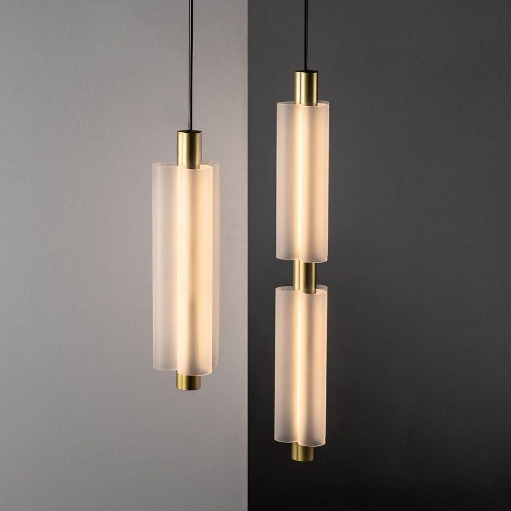 Close view of two gold-ended Clérachic pendants, one single and one double, with frosted white cylinders lit from within.