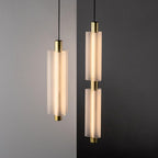 Close view of two gold-ended Clérachic pendants, one single and one double, with frosted white cylinders lit from within.