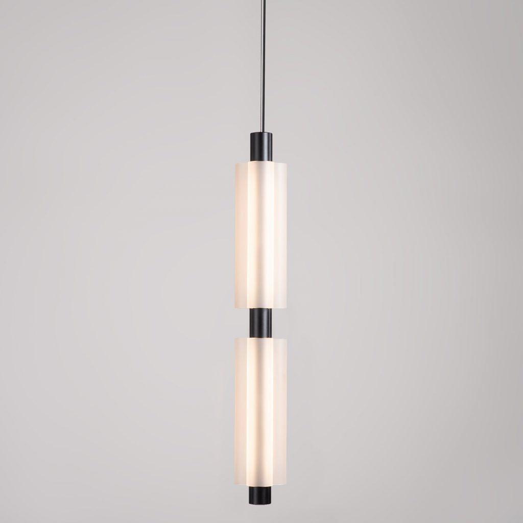 A two-head Clérachic pendant with black fittings, lit from inside, on a soft grey backdrop.