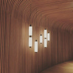 Clérachic pendants of different heights glow warm against a sweeping wall of curved wooden slats.