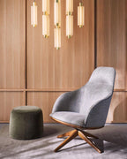 A cluster of gold-ended Clérachic pendants hangs above a grey armchair and a green pouffe, against warm timber panelling.