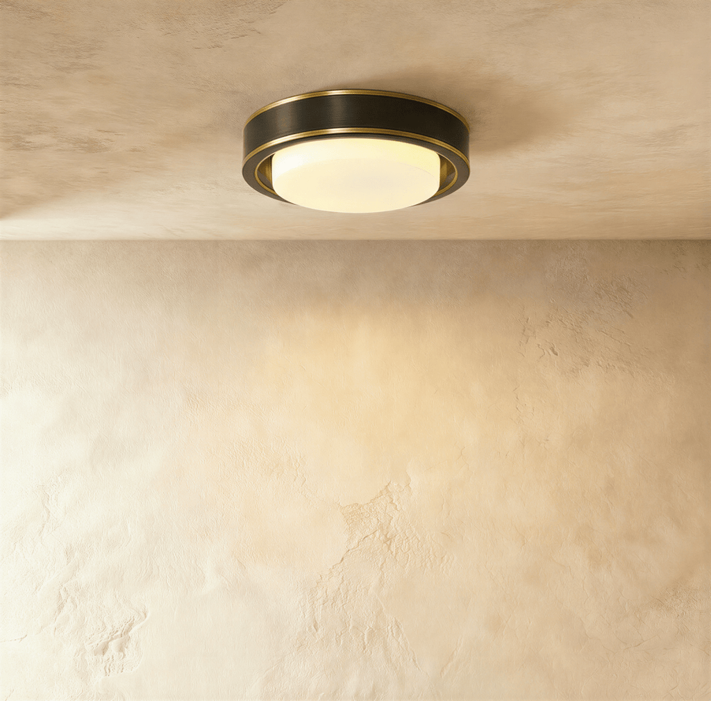 Clérachic larger round flush ceiling light in a dark black finish with fine brass edging and a glowing frosted glass cover.