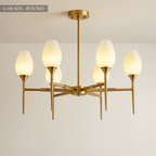 Clérachic six-arm brass chandelier with frosted tulip shades on slim arms, hung from a brass stem and round ceiling plate.