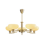 Studio view of this Clérachic chandelier on plain white, five lit beige glass heads on gold arms with a short rod.