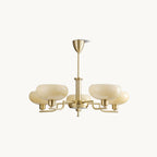 Gold Clérachic chandelier on an off-white backdrop, five beige glass heads and a short brass rod.