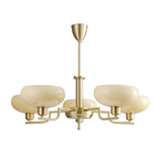 Studio view of a five-head gold Clérachic chandelier with butter-coloured glass domes on brass arms.
