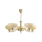 Five-head gold Clérachic chandelier on white, with cream glass domes on bent brass arms.
