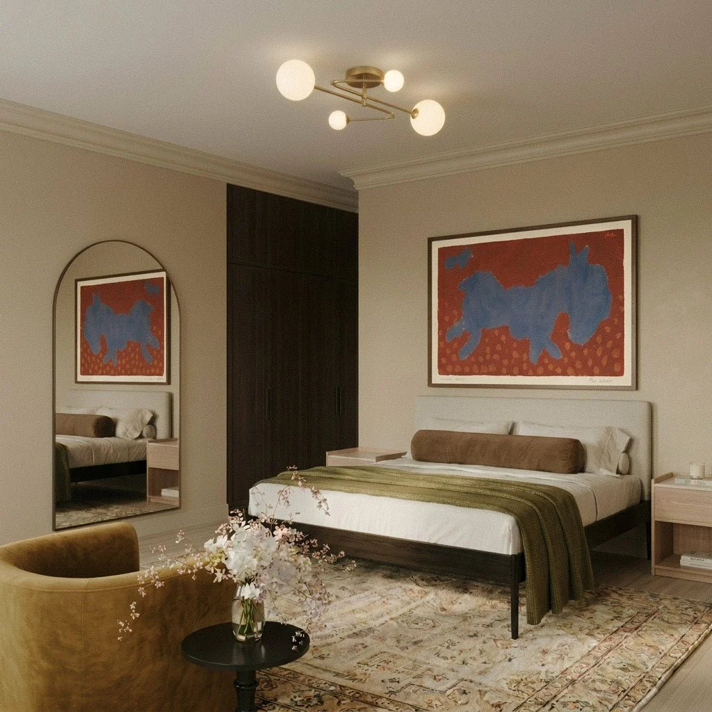 Clérachic four-head brass-toned ceiling light with frosted globes above a bed in a warm bedroom with an arched mirror.