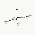 Branching black chandelier from Clérachic with frosted white glass globes on slim arms, hung from a round ceiling plate on a white backdrop.