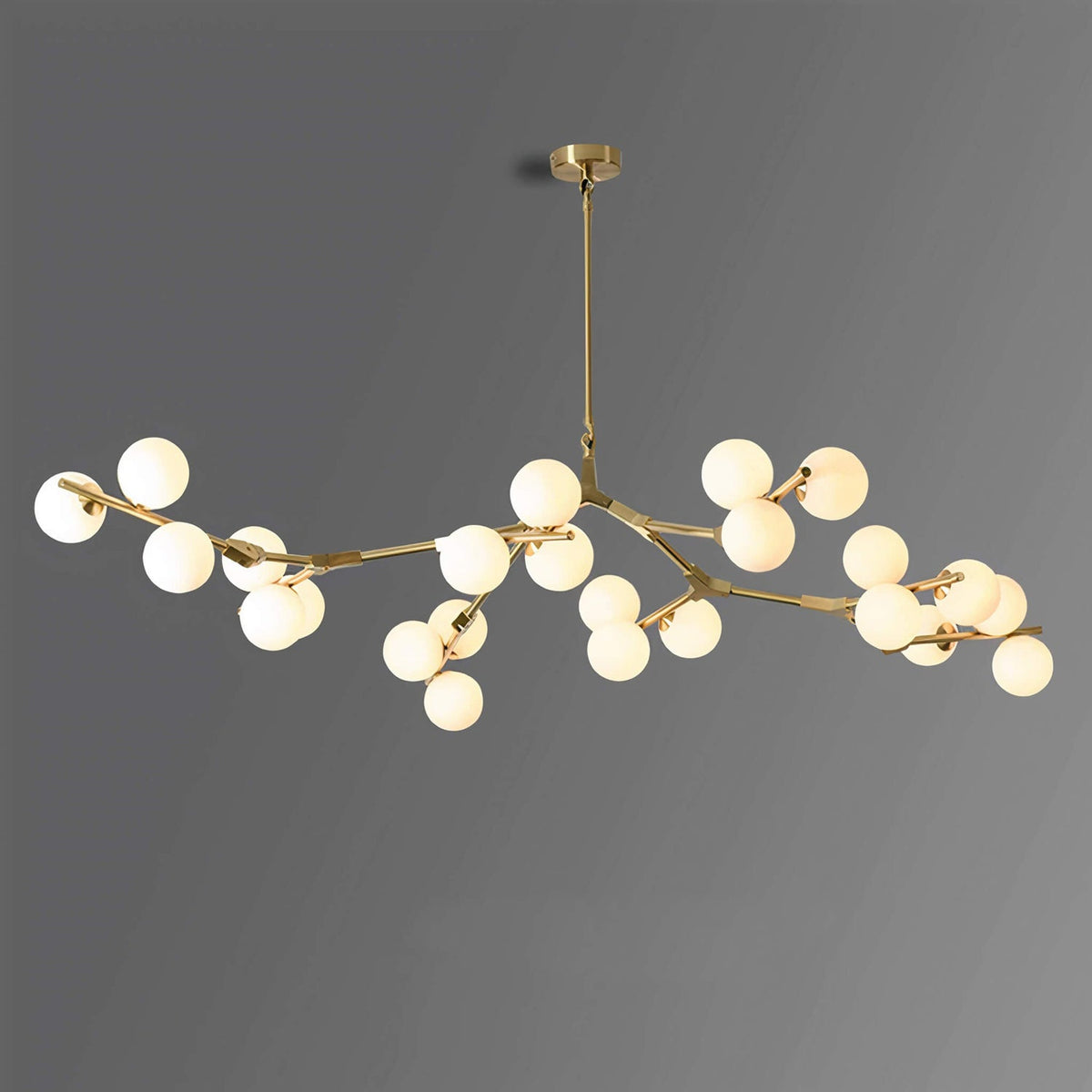 Gold-finish branching chandelier with lit frosted globes, hung from a slim brass rod against a mid-grey backdrop; this Clérachic design.