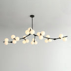Black Clérachic chandelier on a thin rod with many lit frosted globes along long, low branches, against a pale grey wall.
