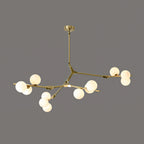 Gold and white three-armed chandelier with lit globes on thin brass branches, hung from a small gold canopy on dark grey; Clérachic.