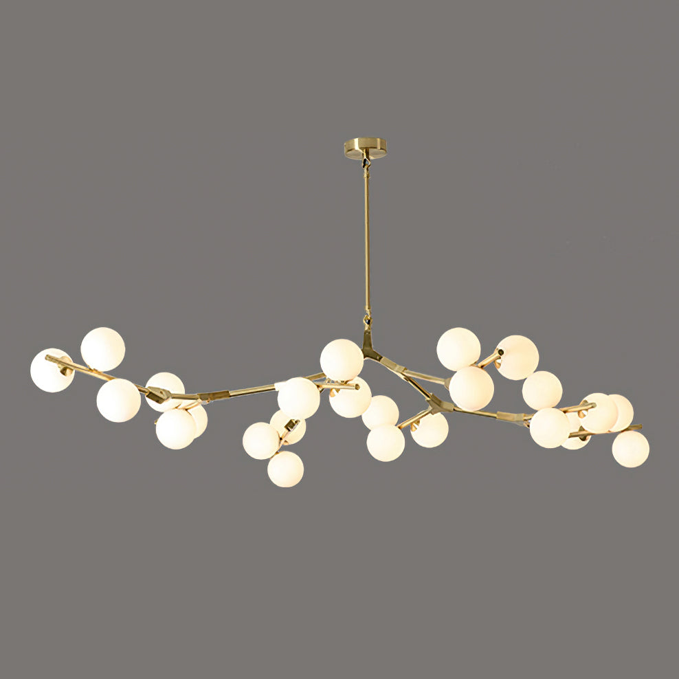 The widest gold and white Clérachic chandelier, with lit white globes clustered along its long brass branches on dark grey.