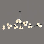 Wide black Clérachic chandelier with frosted glass globes lit in clusters along its low, spreading branches, on dark grey.