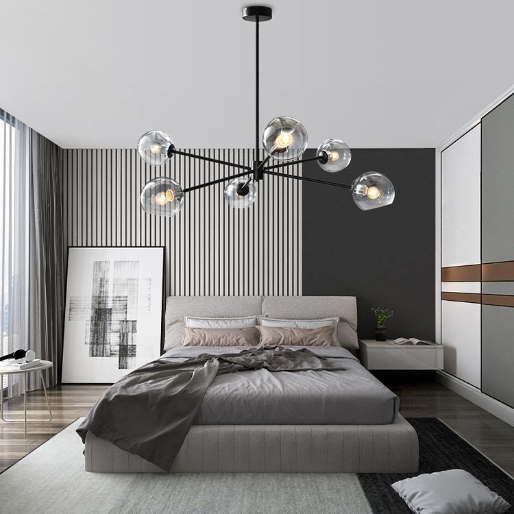 Black six-globe Clérachic chandelier in a bedroom with a slatted wall panel, a grey bed and a framed abstract print.