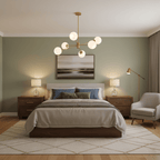 Gold six-light chandelier from Clérachic with white globes above a bed with bedside lamps, in a sage-green bedroom.