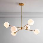 Gold-finish chandelier from Clérachic with white opal globes on angled arms, hung from a slim rod below a plain grey ceiling.