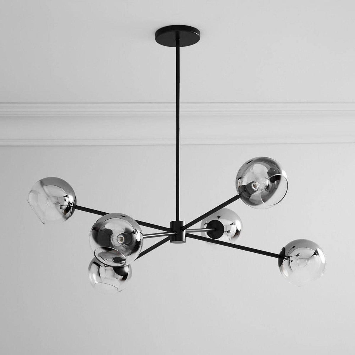 Black six-globe Clérachic chandelier with mirrored smoked shades, seen from below with a white cornice behind it.