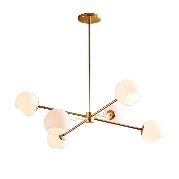 Gold-finish chandelier from Clérachic with six opal white globes on angled arms, shown on a plain white backdrop.