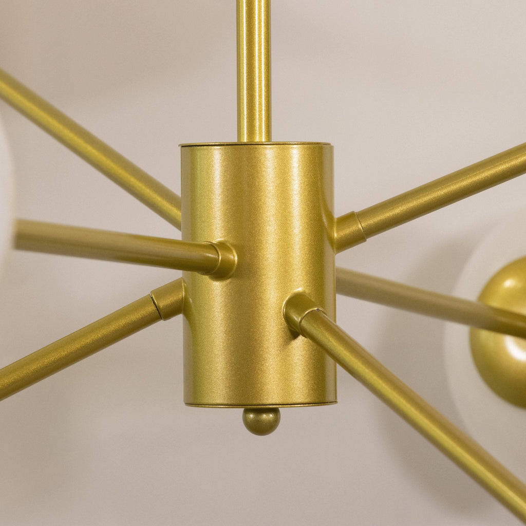 Close view of the textured gold hub on this Clérachic chandelier, with slim gold arms leaving it in several directions.