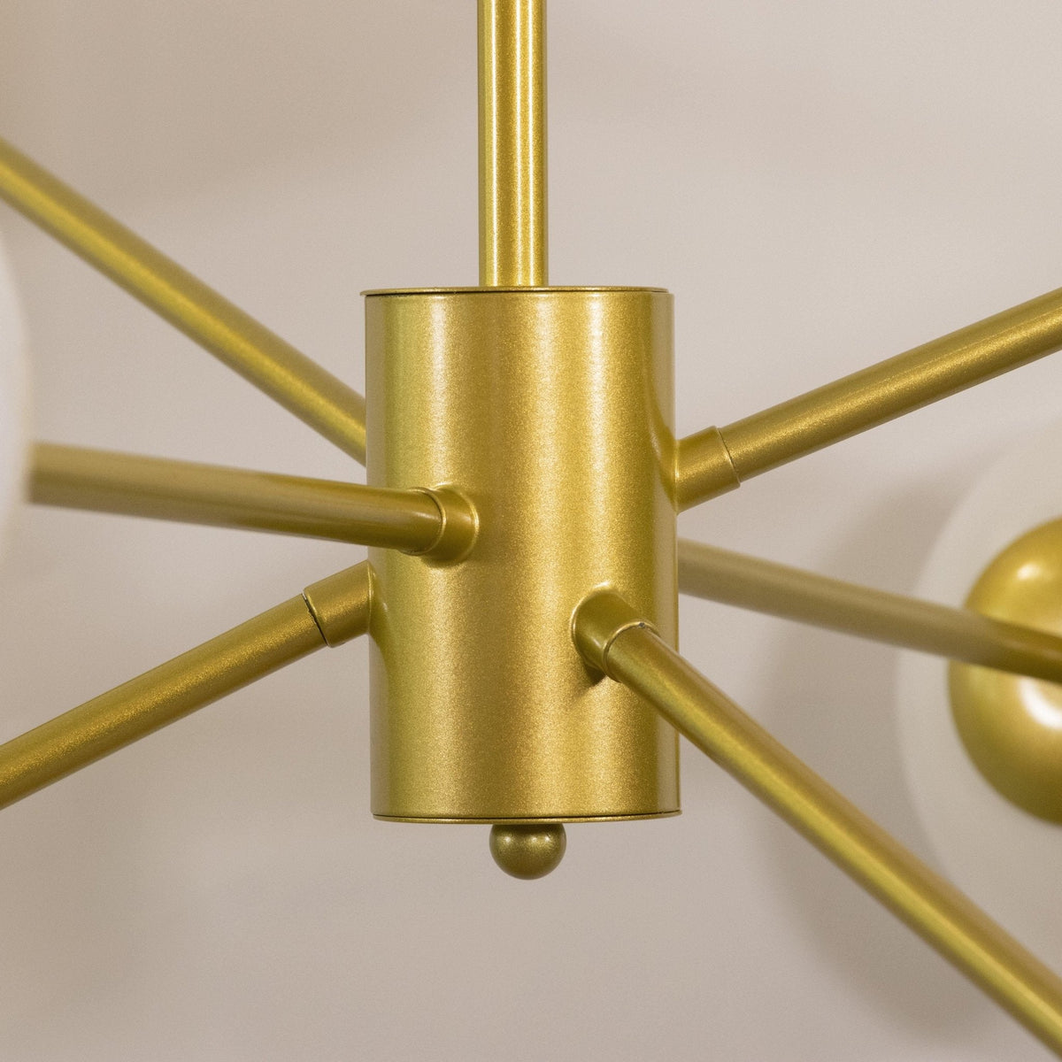 Close view of the textured gold hub on this Clérachic chandelier, with slim gold arms leaving it in several directions.