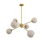 Six-light gold chandelier from Clérachic with opal white globes on slim arms, shown from a low angle on white.