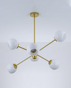 Gold six-globe Clérachic chandelier with white shades, seen from below, with a bulb visible inside the centre one.