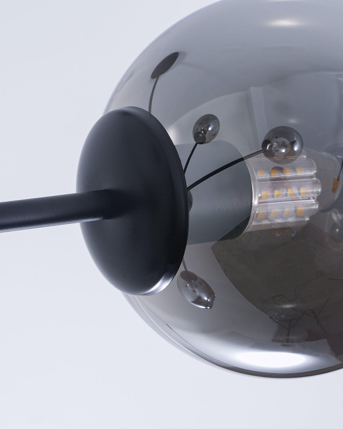 Close view inside a smoked glass globe on this Clérachic chandelier, with the black socket cup and a bulb visible.