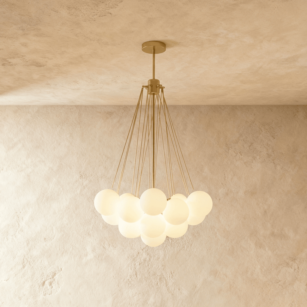 Clérachic cluster chandelier with frosted white glass spheres hanging from fine gold-toned rods, lit warmly against limewash.