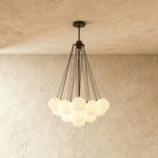 Clérachic cluster chandelier with frosted glass spheres hanging from slim black rods and a black canopy, glowing softly.