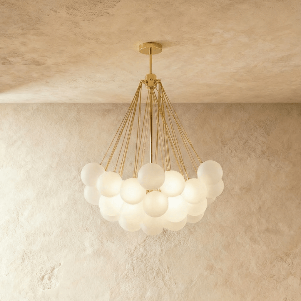 Clérachic larger cluster chandelier with many frosted glass spheres on gold-toned rods and a round gold canopy, lit.