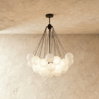 Clérachic larger cluster chandelier with many frosted glass spheres hung from black rods and a black canopy, glowing.