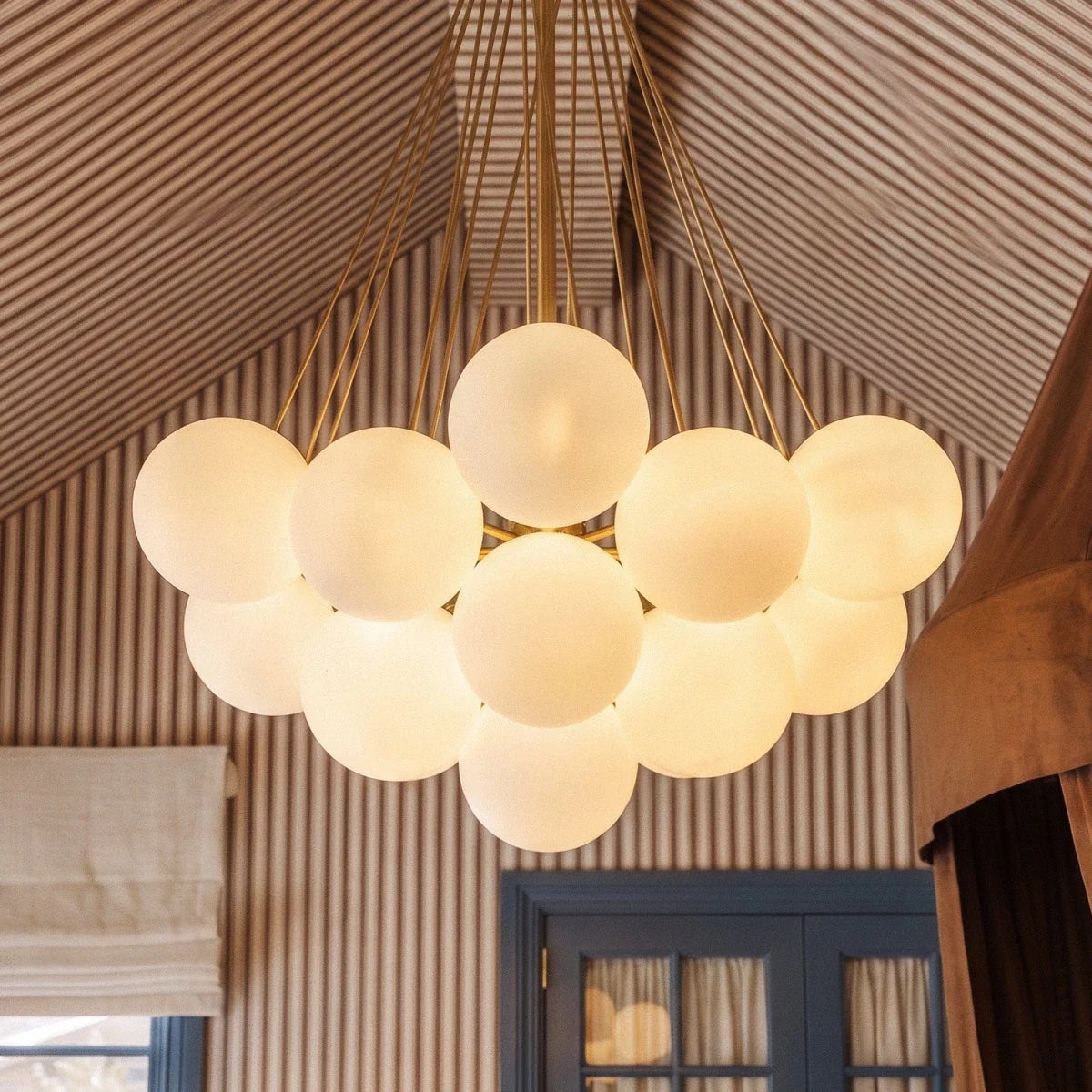 Close view of a Clérachic gold-toned cluster chandelier, showing smooth frosted glass spheres and fine rods meeting at the stem.