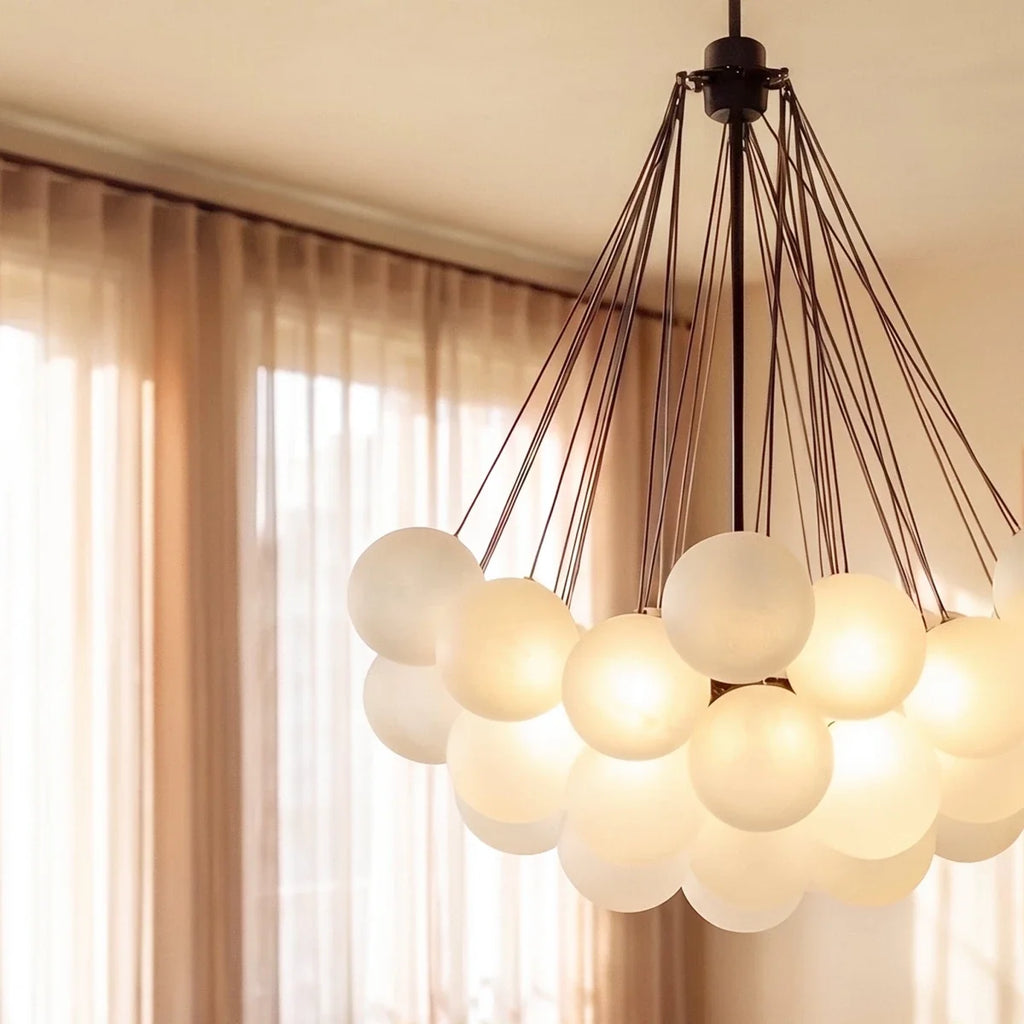 Close view of a Clérachic black cluster chandelier, showing frosted glass spheres glowing beneath fine black rods and canopy.