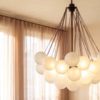 Close view of a Clérachic black cluster chandelier, showing frosted glass spheres glowing beneath fine black rods and canopy.