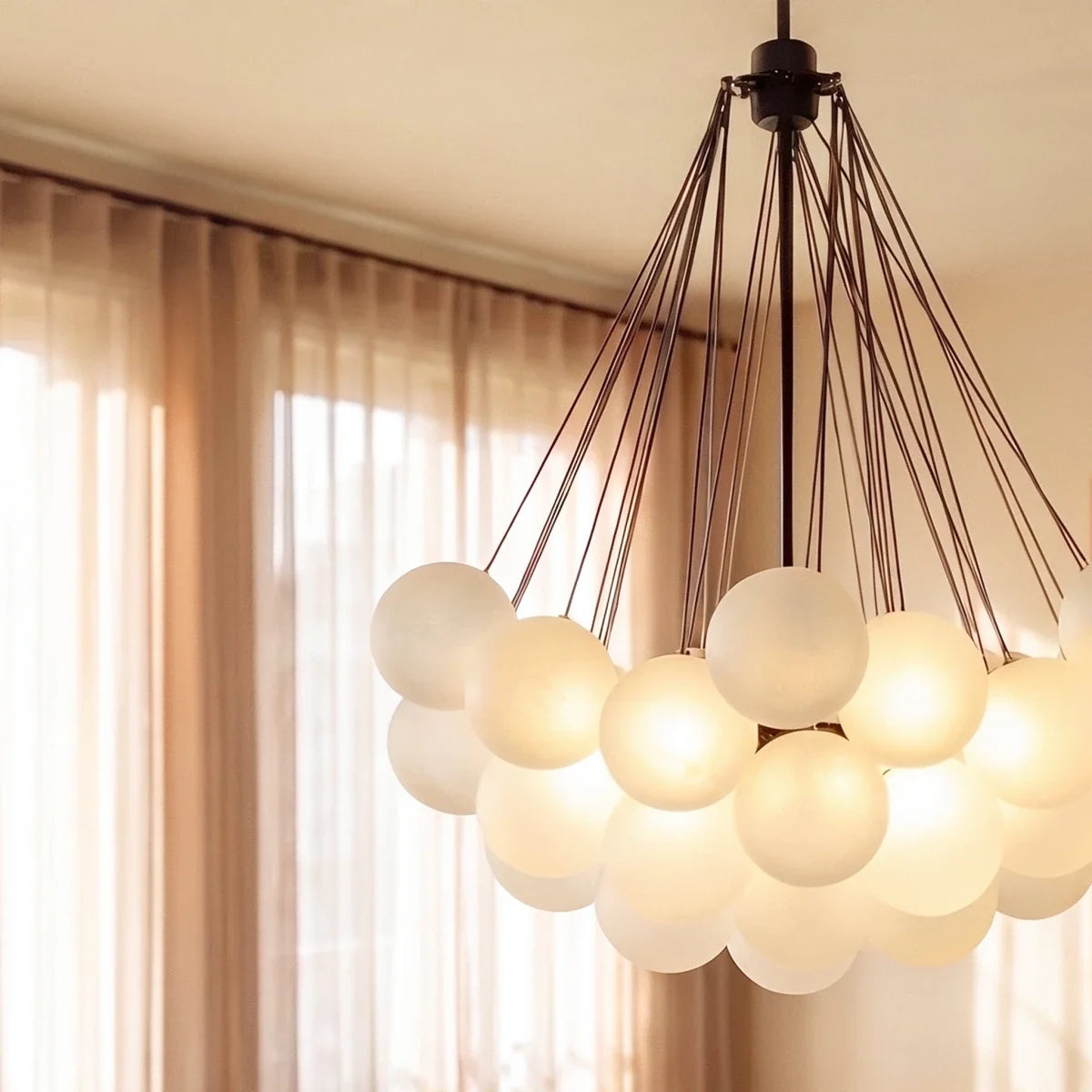 Close view of a Clérachic black cluster chandelier, showing frosted glass spheres glowing beneath fine black rods and canopy.