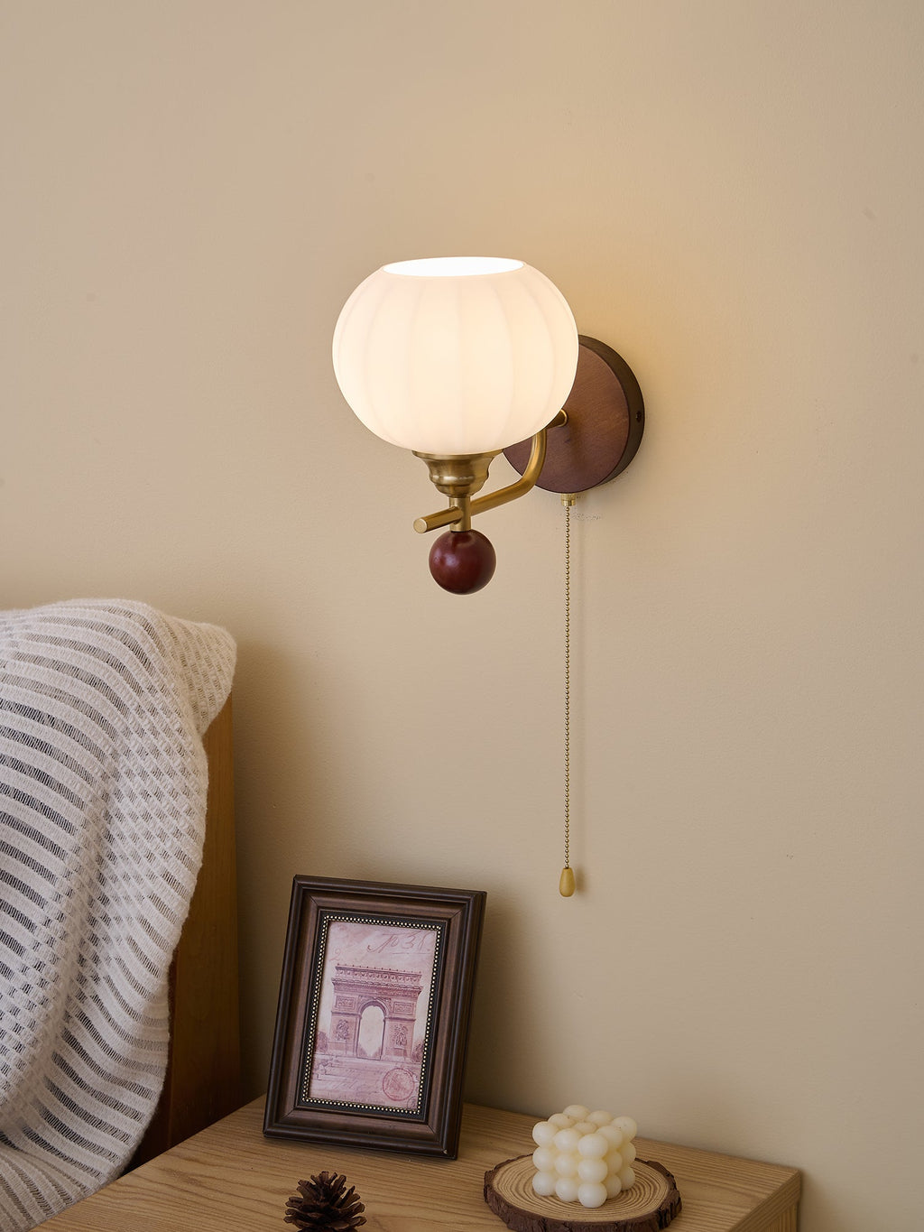 Clérachic wall light with a ribbed globe seen from slightly below, lit warm above a framed print and a small candle.