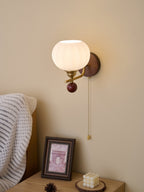 Clérachic wall light with a ribbed globe seen from slightly below, lit warm above a framed print and a small candle.