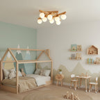 Clérachic wood-frame ceiling light with frosted globes in a child's room, with a house-shaped bed frame, mountain mural and small wooden table.